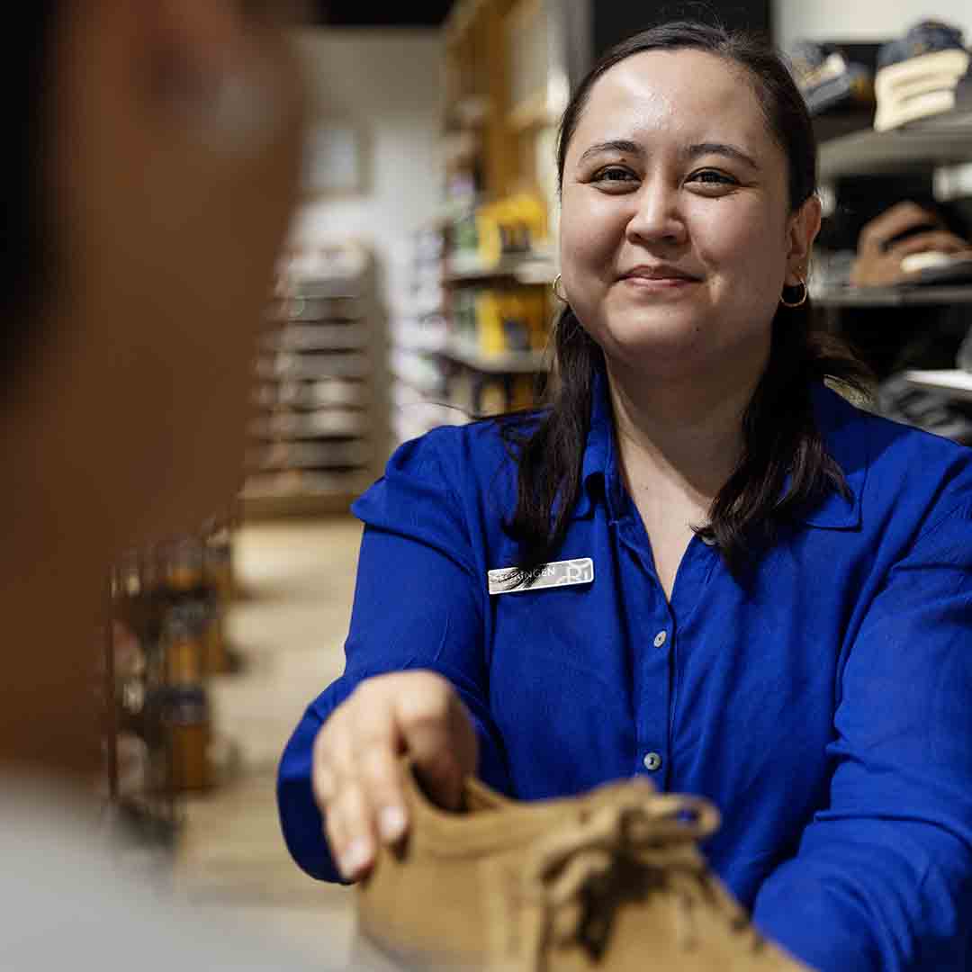 Employee from Skoringen in Frederiksberg gives a customer a pair of shoes.